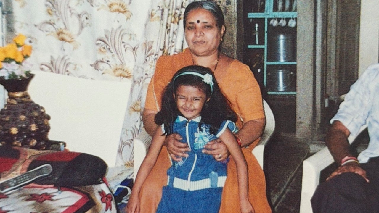 Mishwa Bhavsar as a child being held by her grandmother in a living room.. 