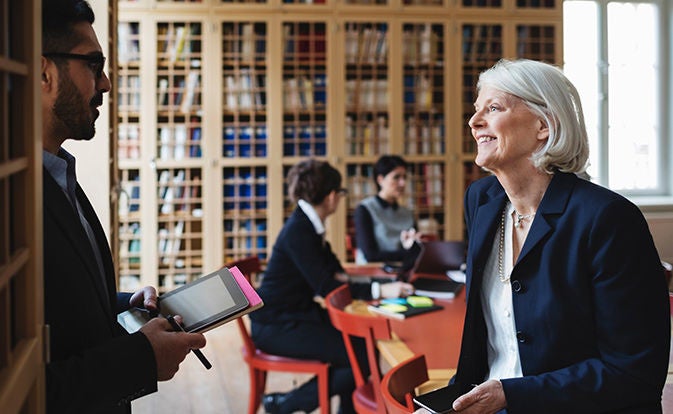 Professional speaking with seated coworkers in a modern office.