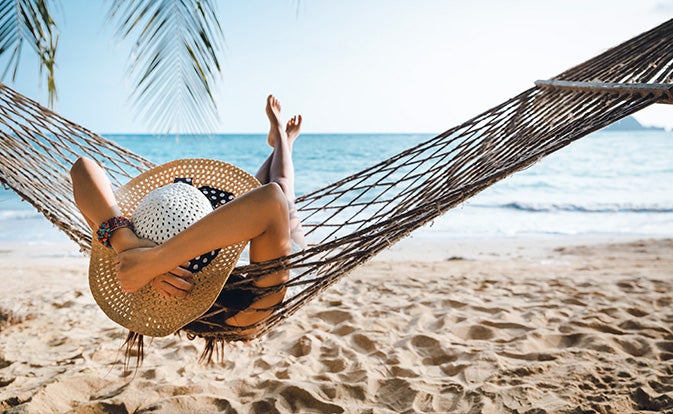 traveler relaxing in hammock on summer beach.