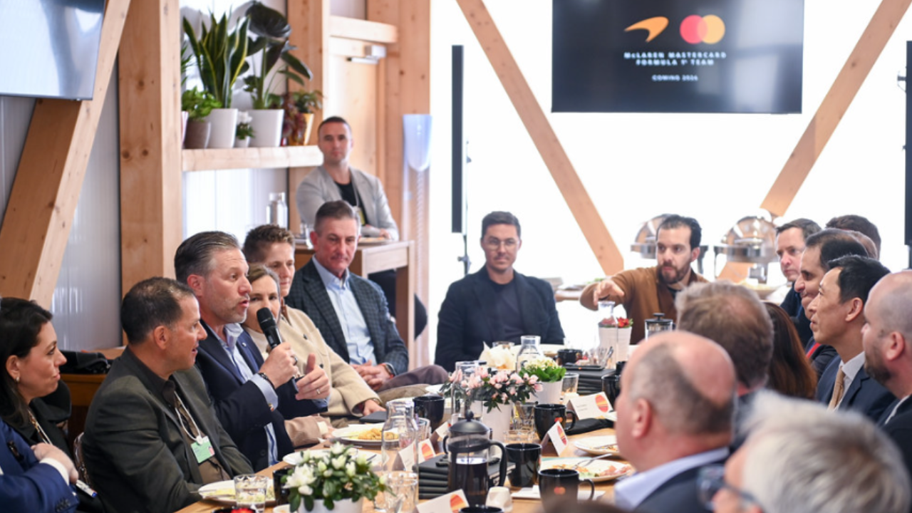 Zak Brown is seated at a table with other people. at a Davos event. 