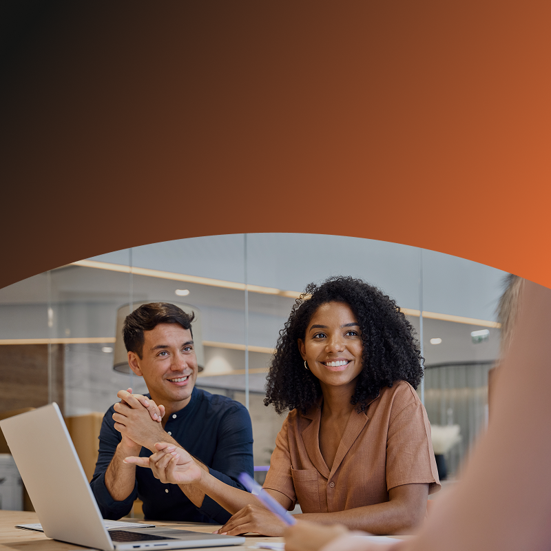 Happy man and woman sitting at a table with a laptop discussing