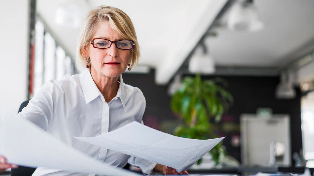 Mature businesswoman examining documents at a desk.