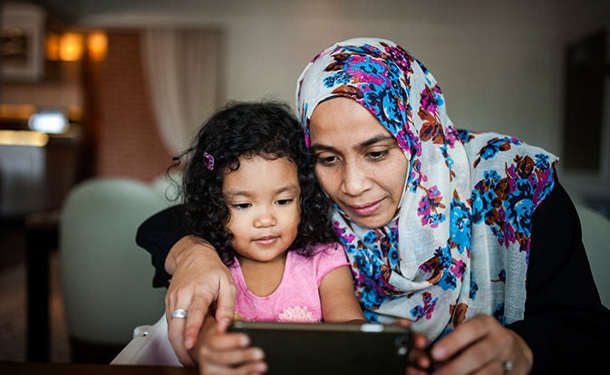Woman using smartphone with toddler.