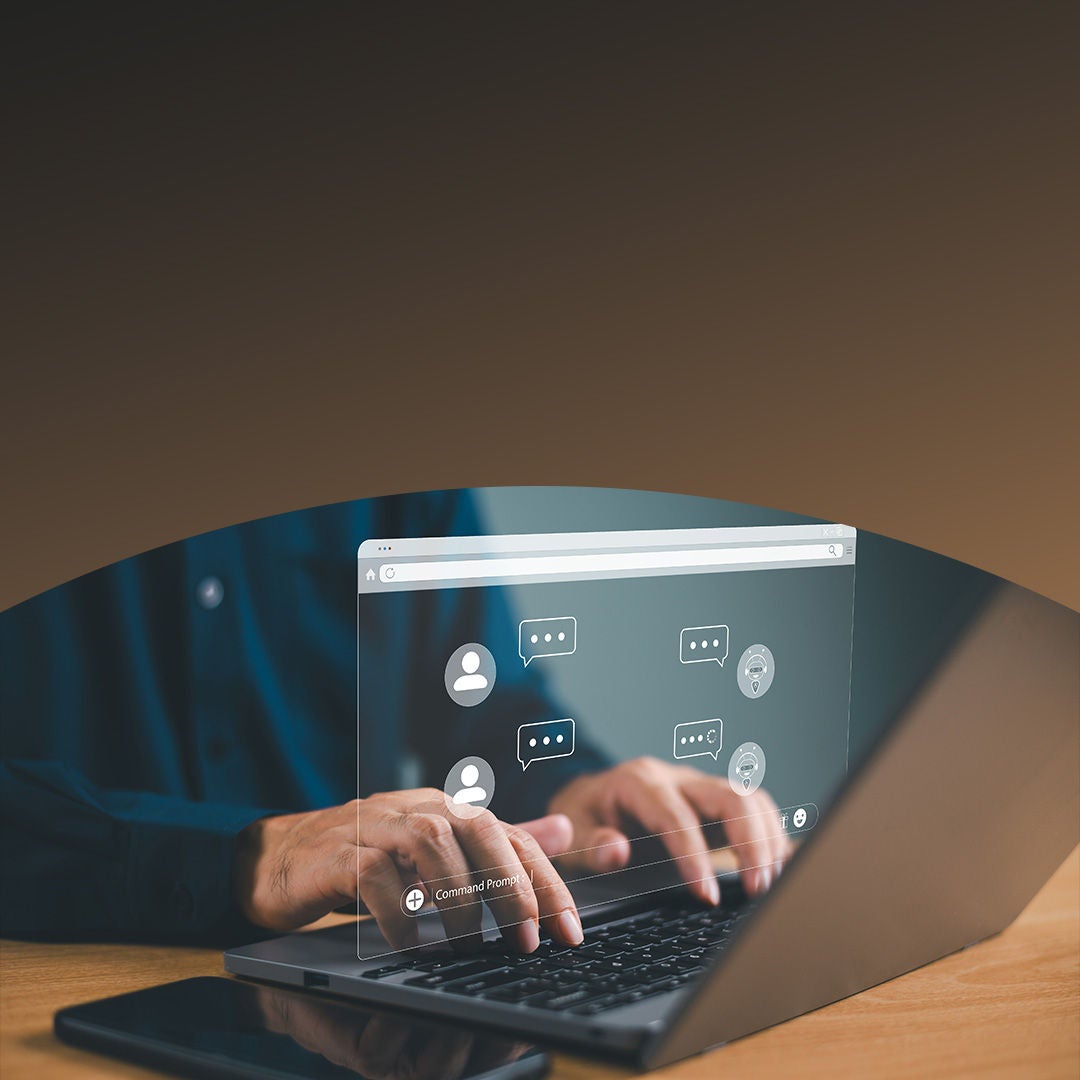 Manos escribiendo en una computadora portátil con un chat holográfico que proyecta íconos de usuario virtuales y burbujas de diálogo.