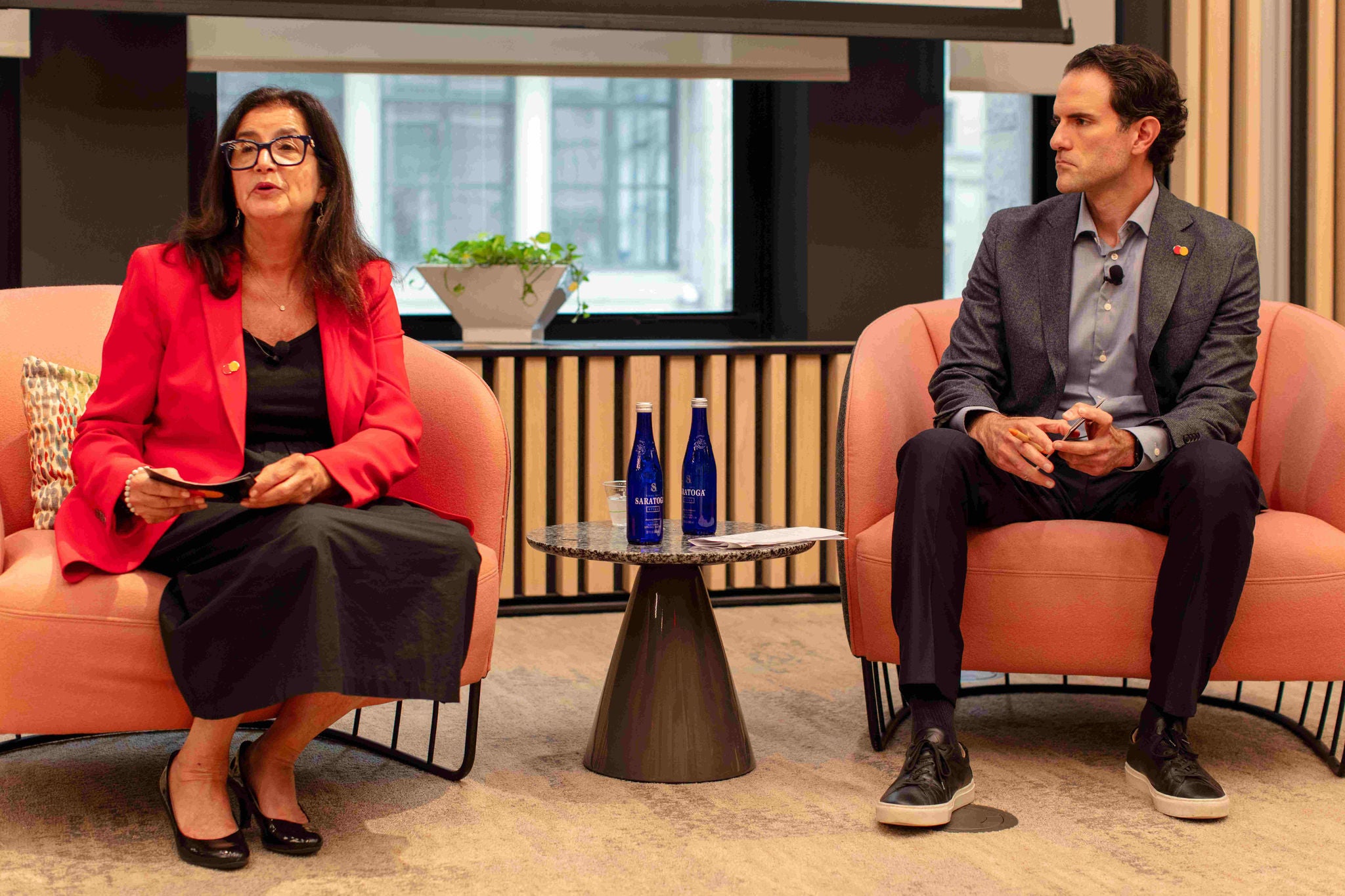 Ginger Siegel and Jonathan Fantini-Porter sit in chairs and speak to the audience at the CNBC Playbook event. 