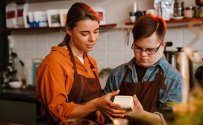 Dos empleados del restaurante con delantales examinan el progreso de una transacción en un terminal de pago con tarjeta.