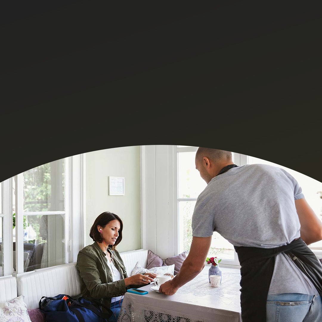 woman paying waiter at cafe table.