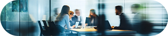 Blurred image of several people engaged in a discussion in a meeting room.