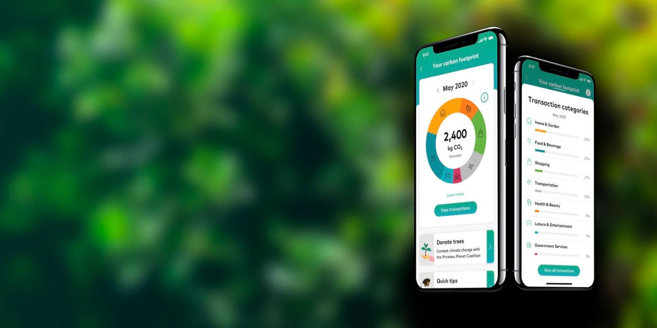 Two smartphones display an app showing a carbon footprint dial and a list of transaction categories, against a blurred green background.