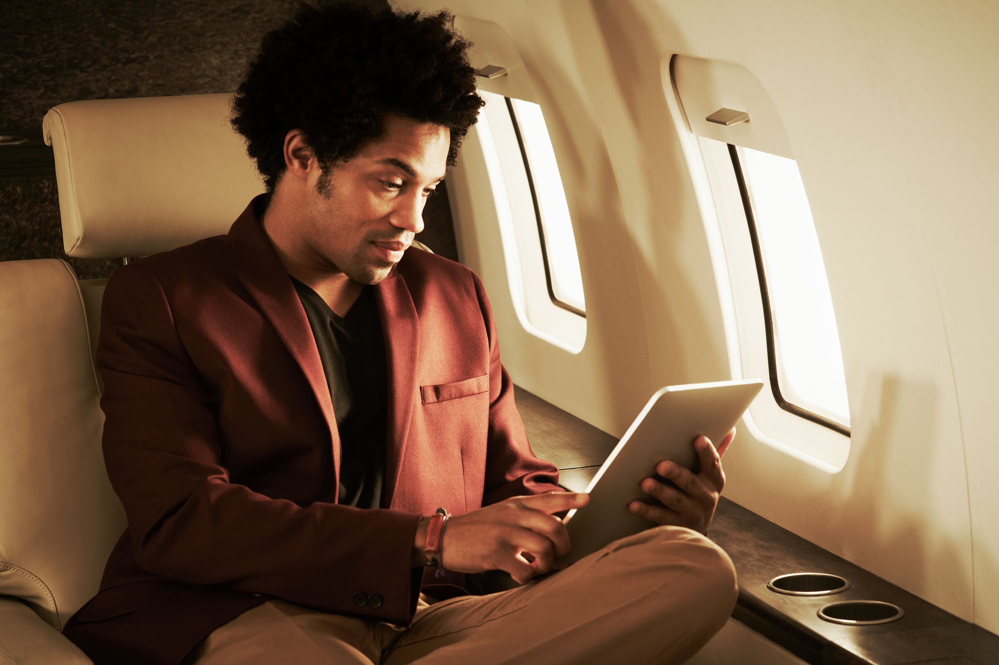 A man travelling in plane & doing something on tablet