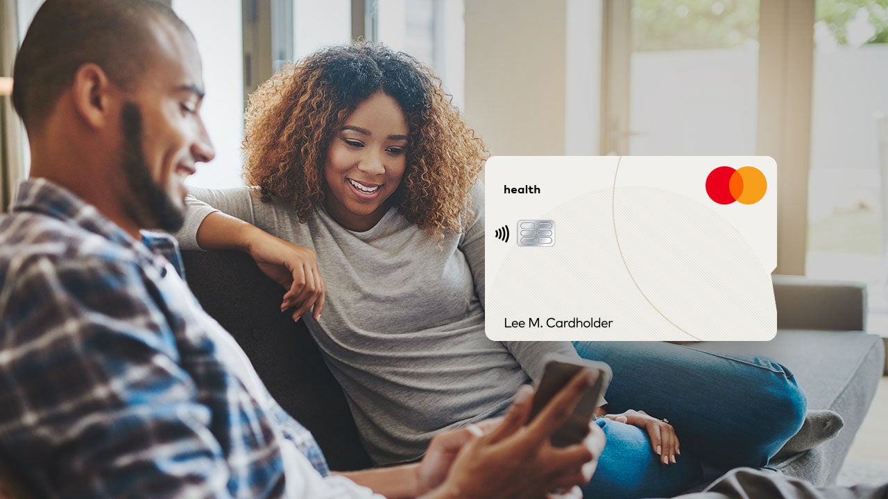 Two people looking at mobile phone with Mastercard card in the foreground.