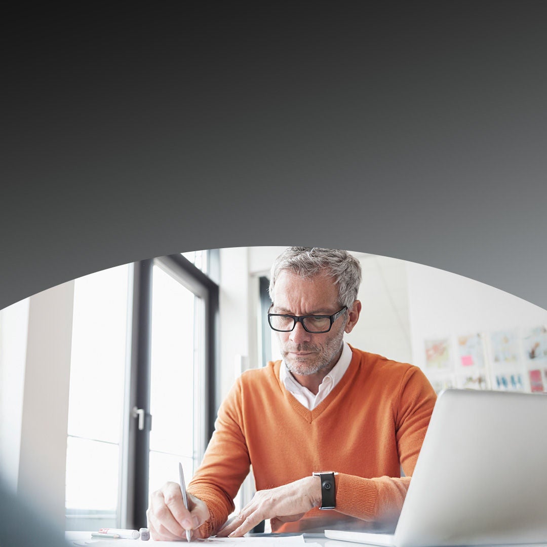 Man sitting in office working with laptop and smart watch