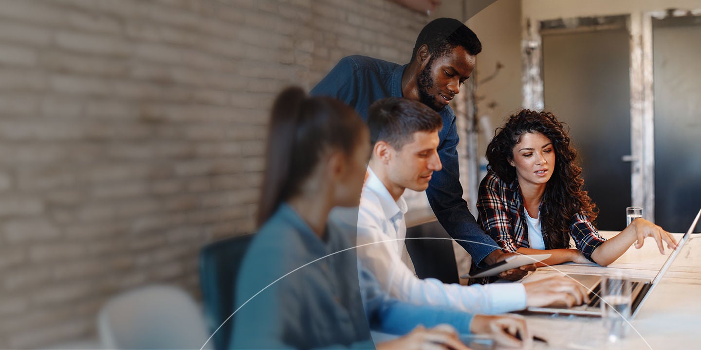 Group of people working collaborating around a laptop.