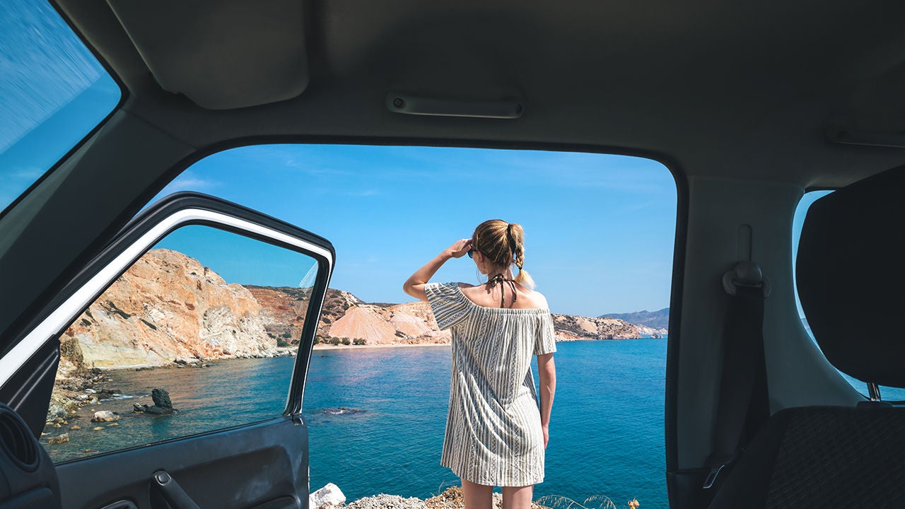 donna appoggiata su auto in paesaggio montuoso