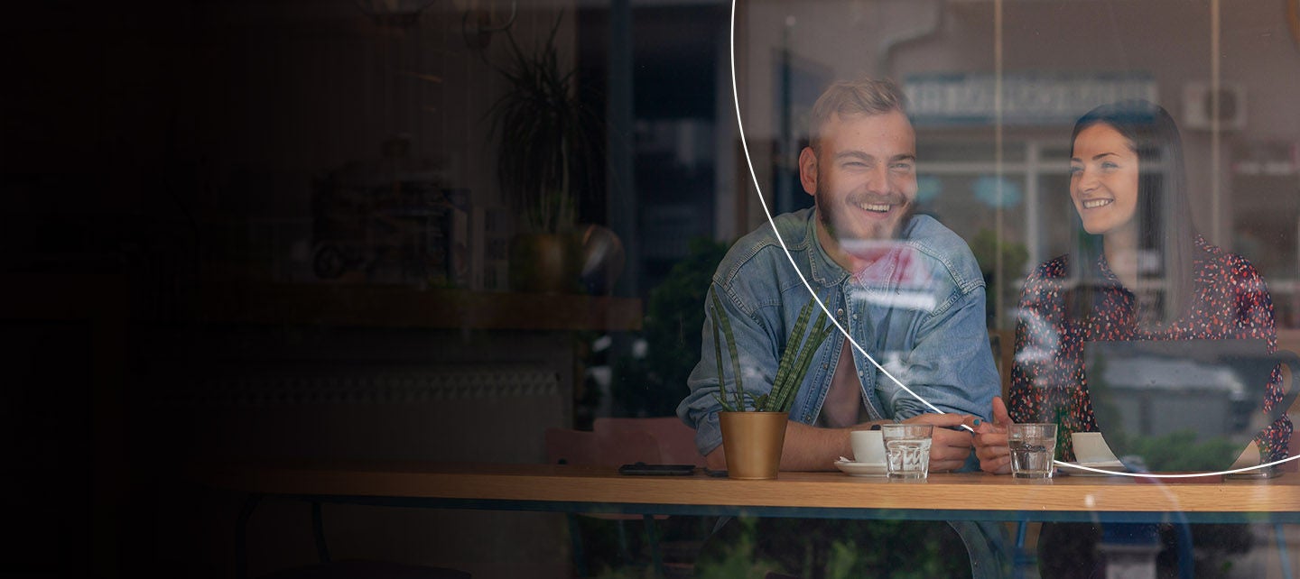 Par sjedi u kafiću dok ih posmatramo kroz staklo.