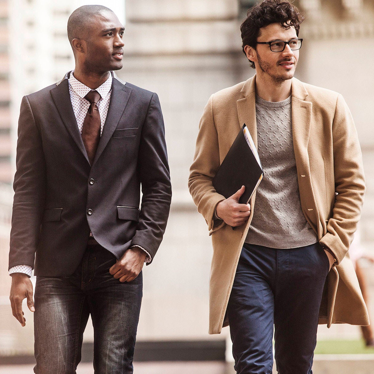 Two professionally dressed coworkers walking side by side outdoors.