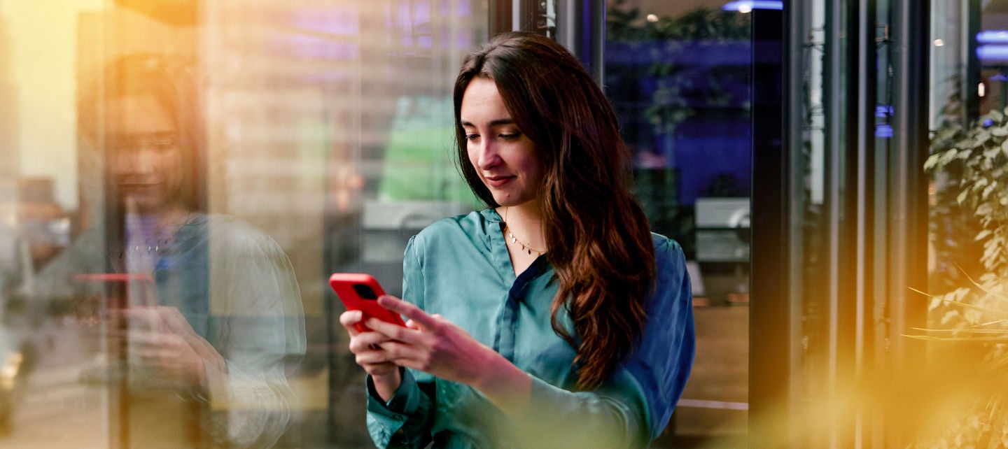 Woman on her phone leaning against a window