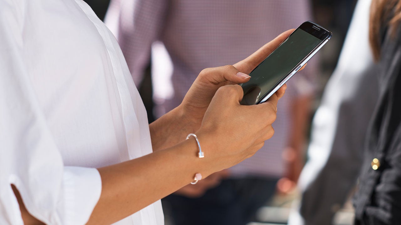 Et nærbillede af en persons hænder, der holder en mobiltelefon.