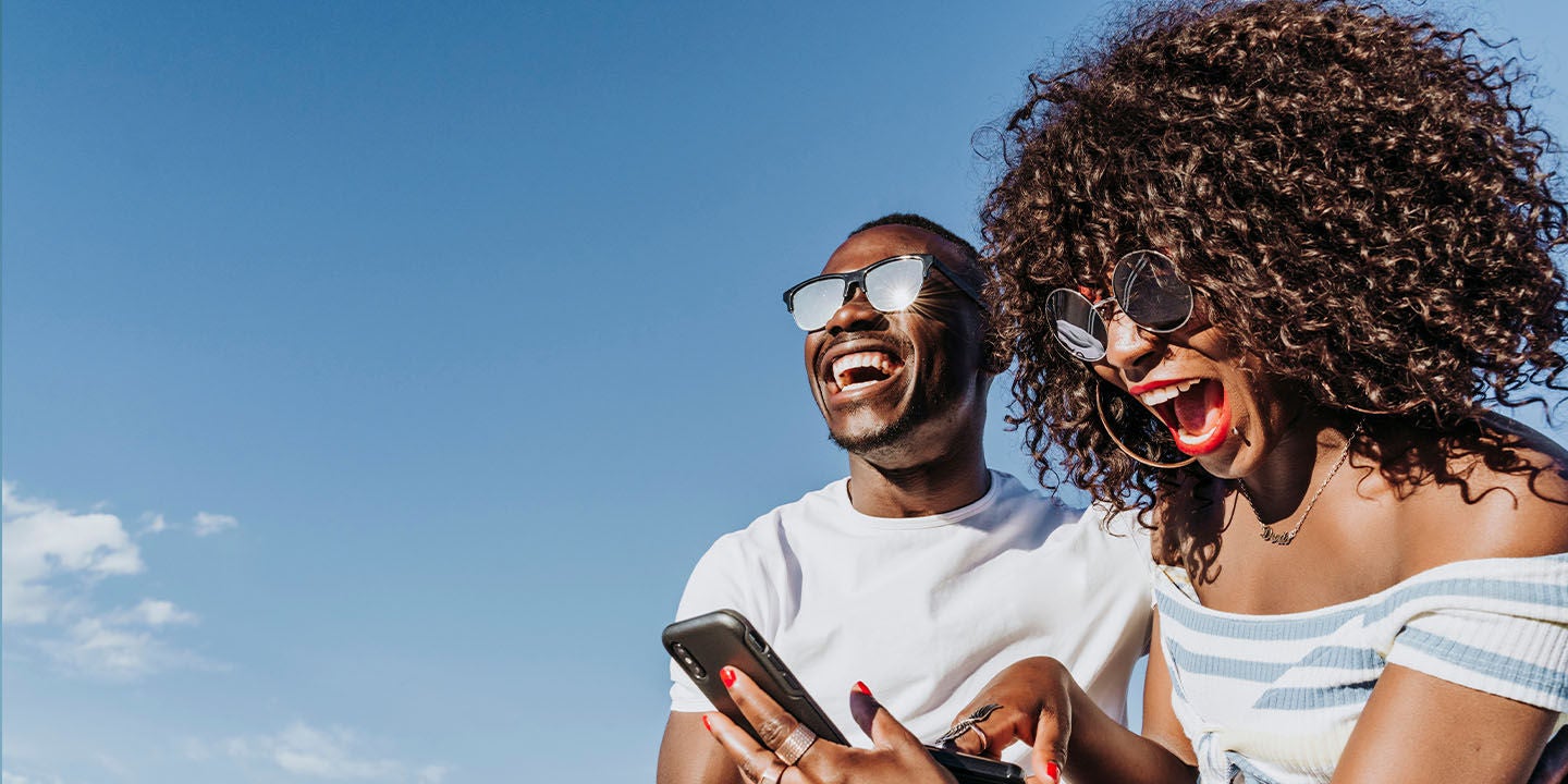 Happy man and woman laughing while looking at a phone