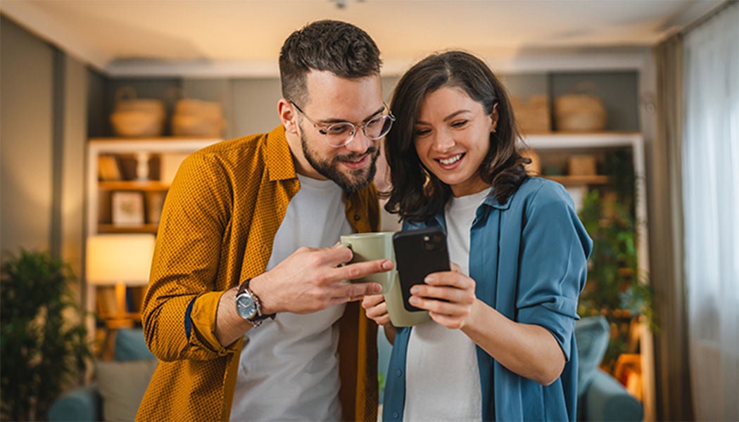 A man and a woman smiling while looking at a phone