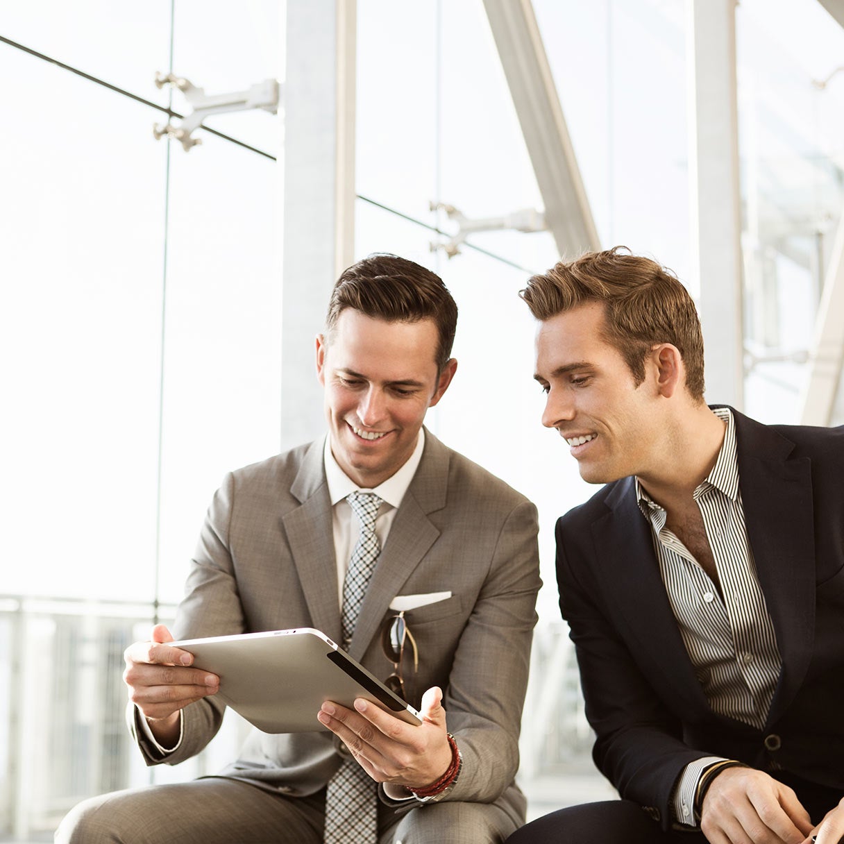Two colleagues in suits looking at a notepad together.