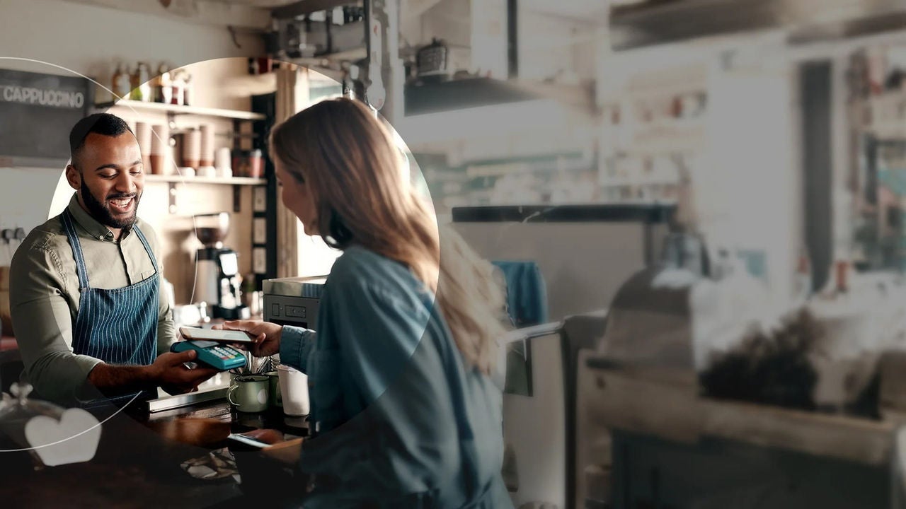 אישה משלמת לבריסטה בבית קפה באמצעות הטלפון.