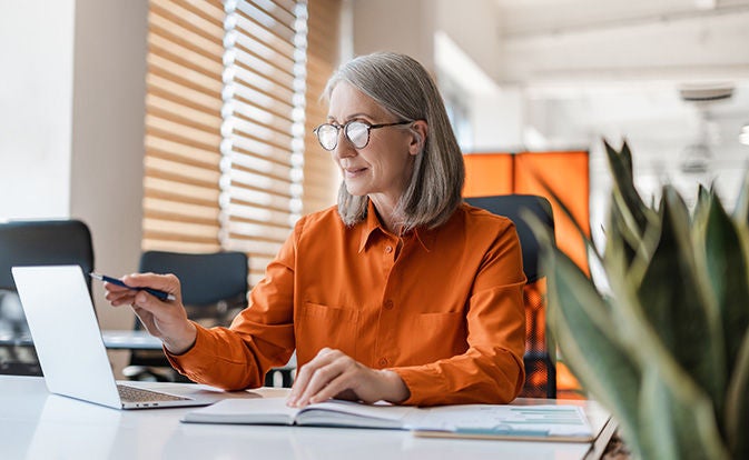 Confident senior woman manager using laptop computer in office.