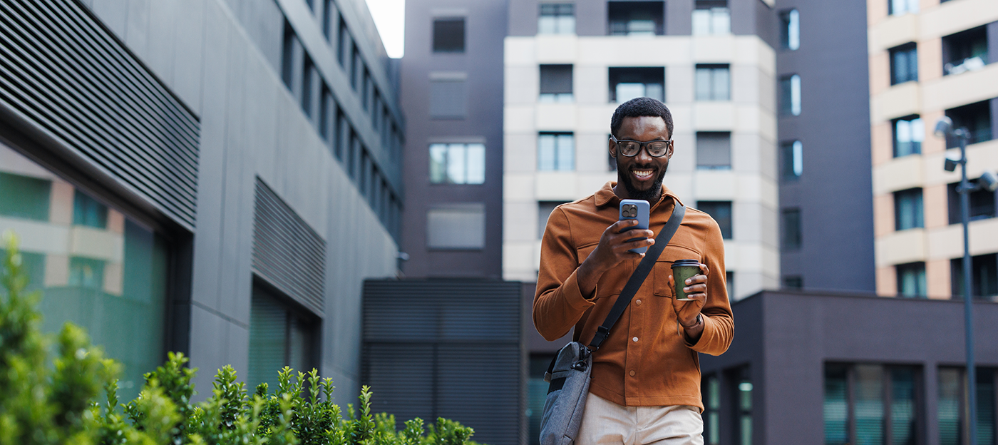 Man walking browsing his phone with a coffee in hand