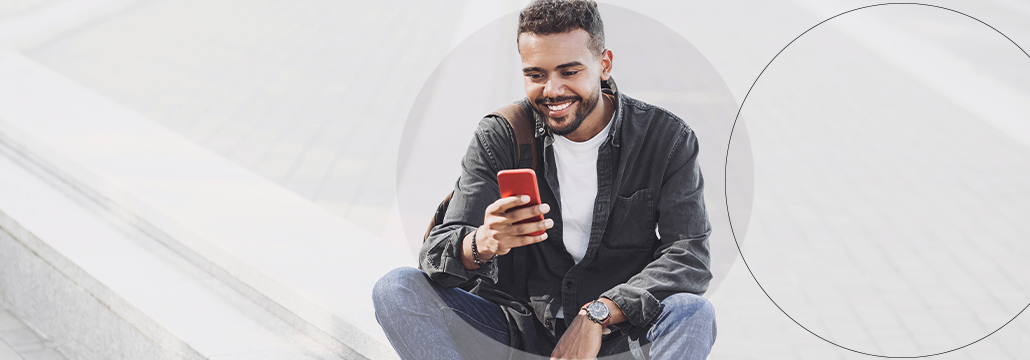 Mann, der draußen sitzt und auf sein Handy schaut