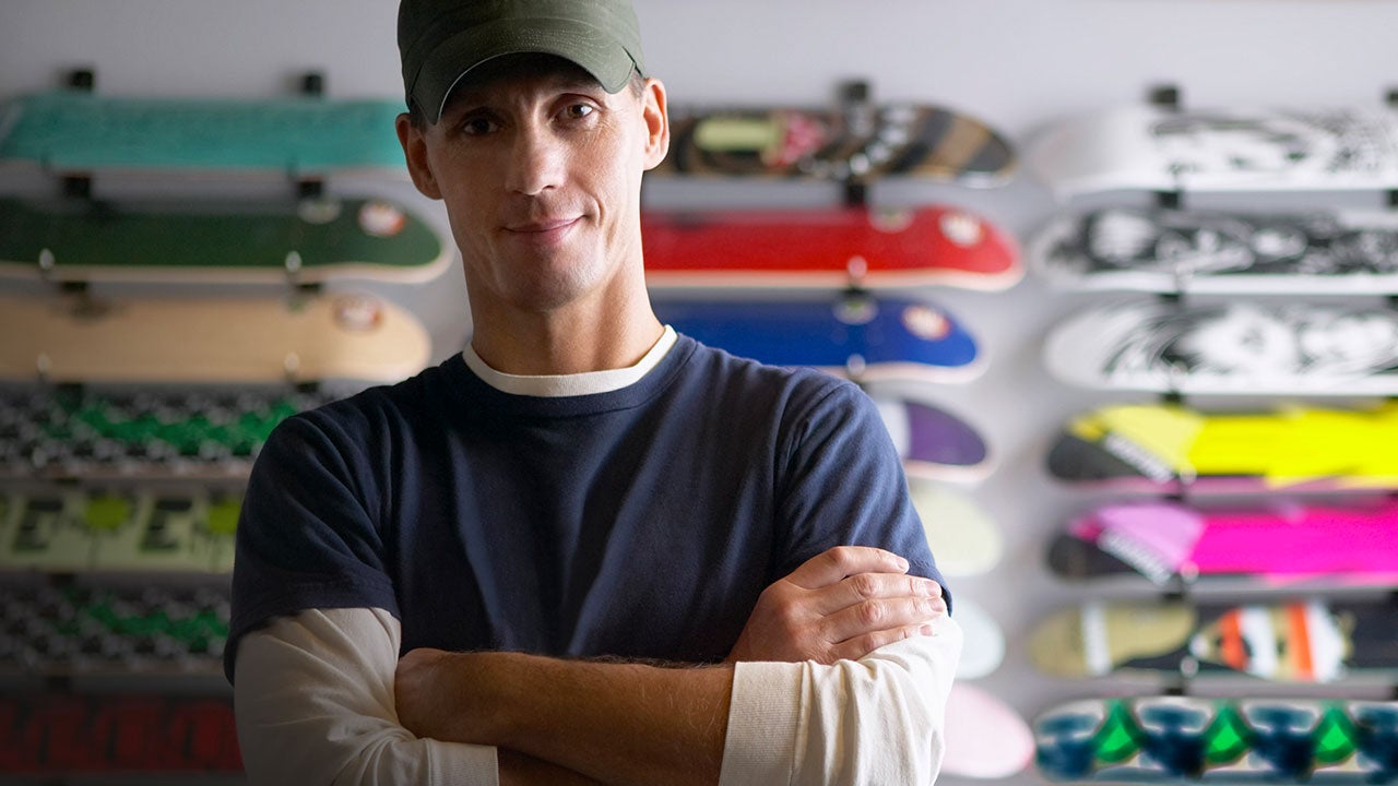 Male owner in his store selling skateboards.