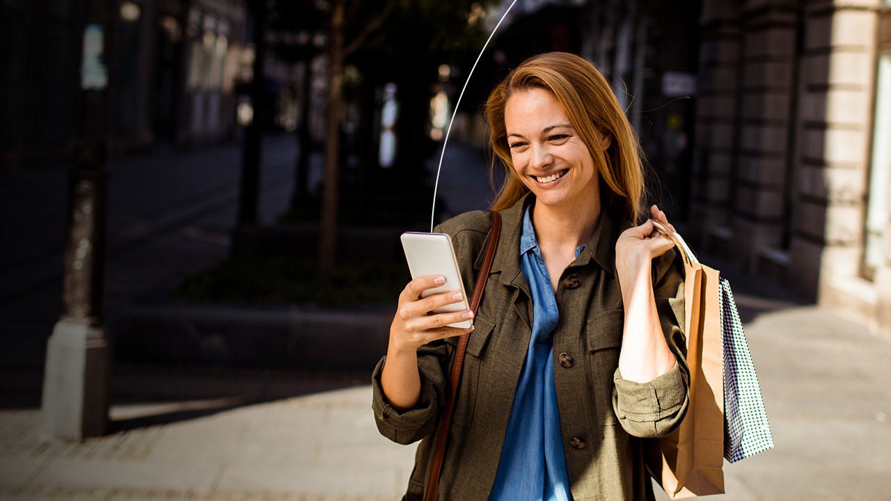 Kobieta przegląda telefon wychodząc ze sklepu