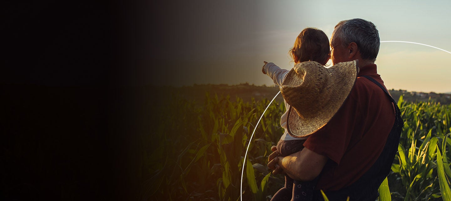 Muškarac i dijete u polju gledaju u zalazak. 