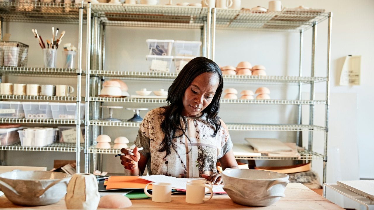 A woman looks over paperwork in her pottery studio. 