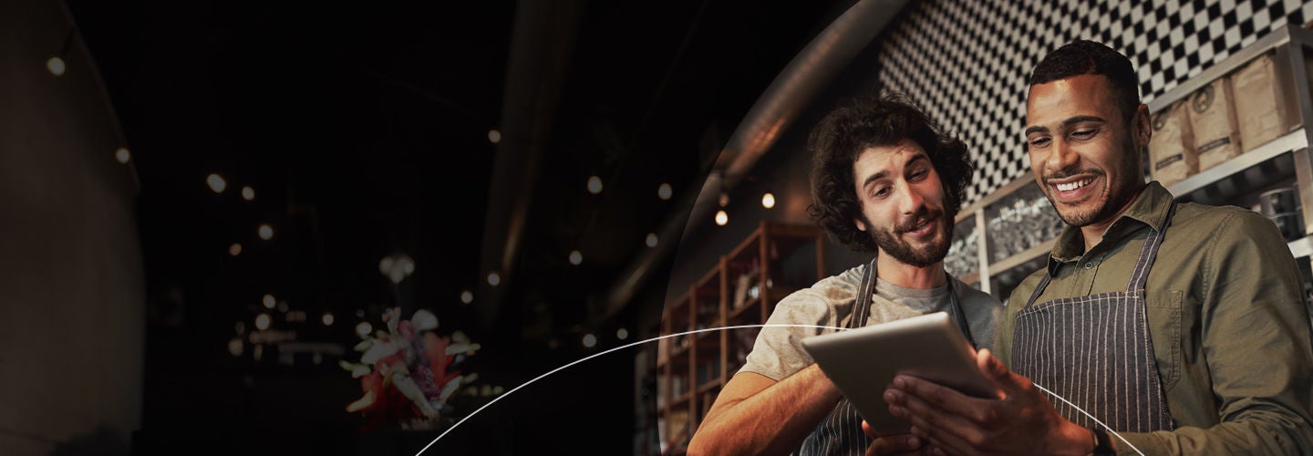 Two men working in a coffee shop looking at a tablet