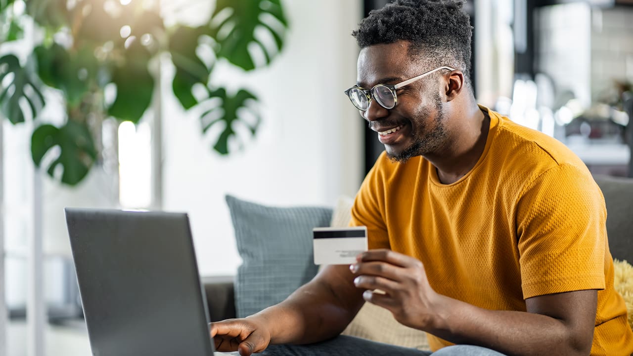 smiling man shopping online with a credit card