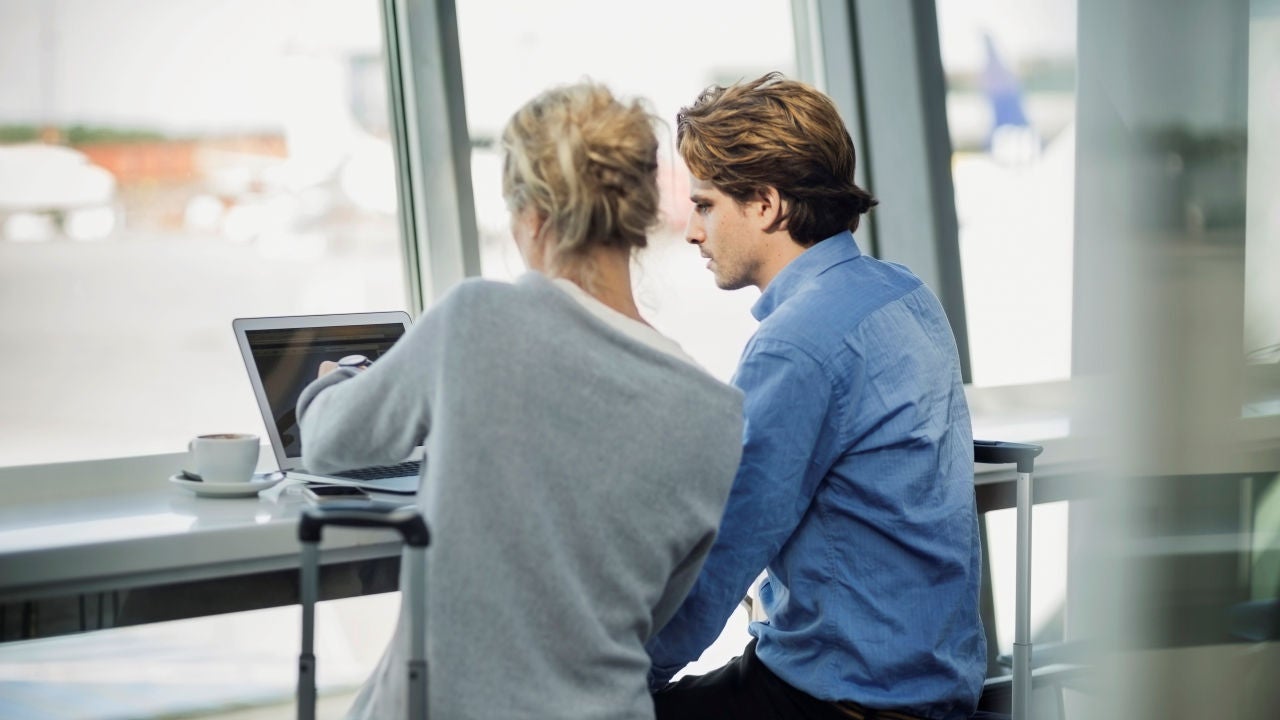 Two colleagues look at a laptop together. 