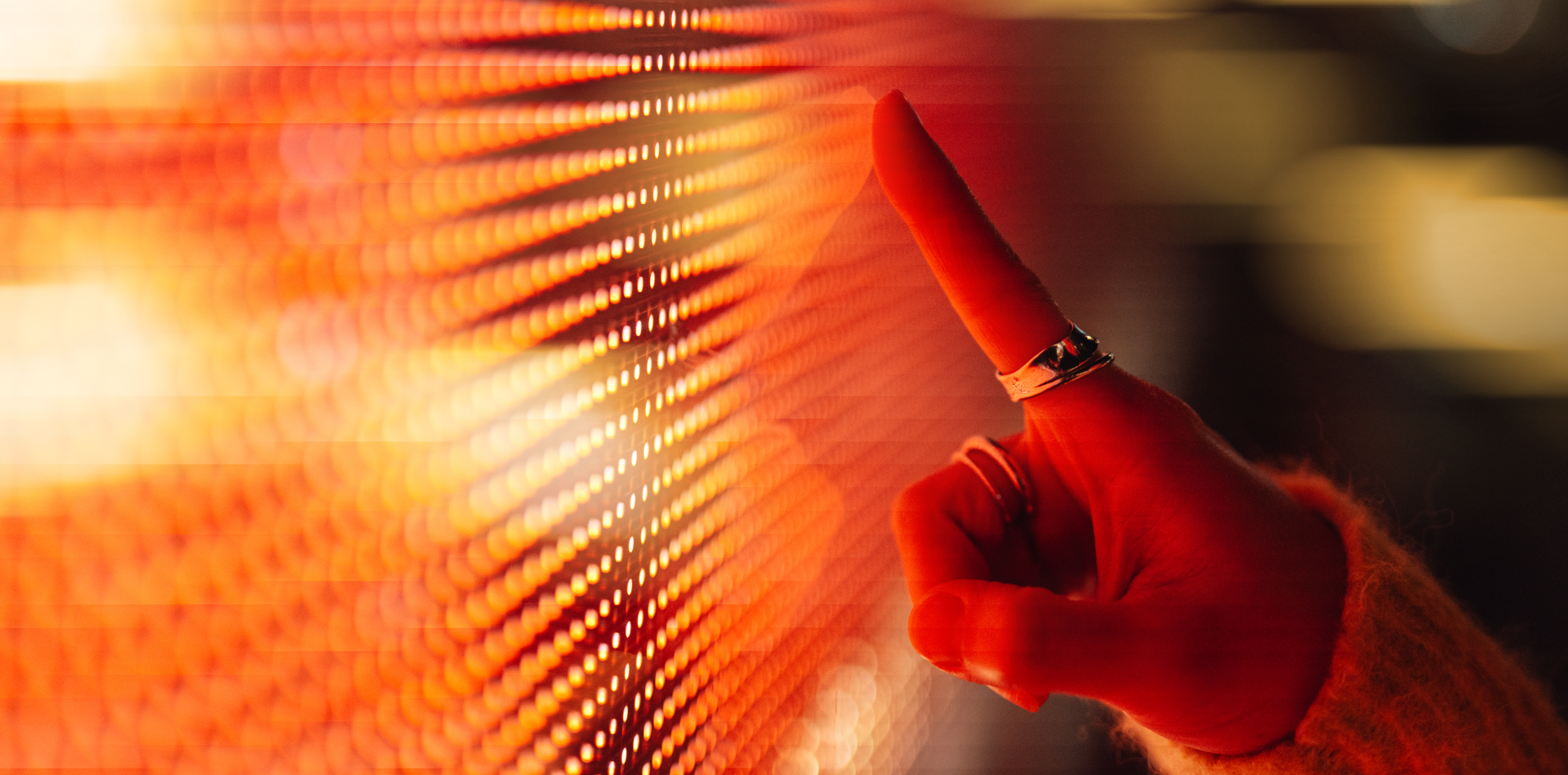 A person touches a glowing red and orange LED panel, creating a sense of interaction with technology.