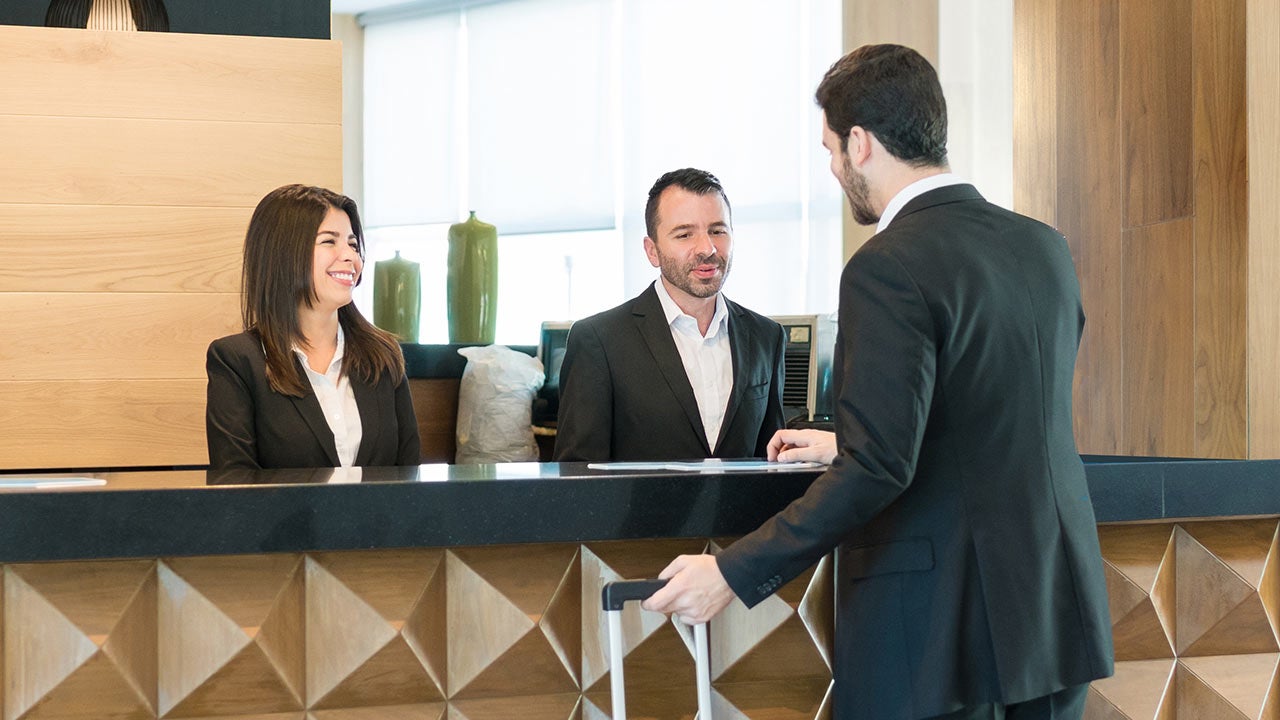 Zwei Männer und eine Frau an der Rezeption eines Hotels