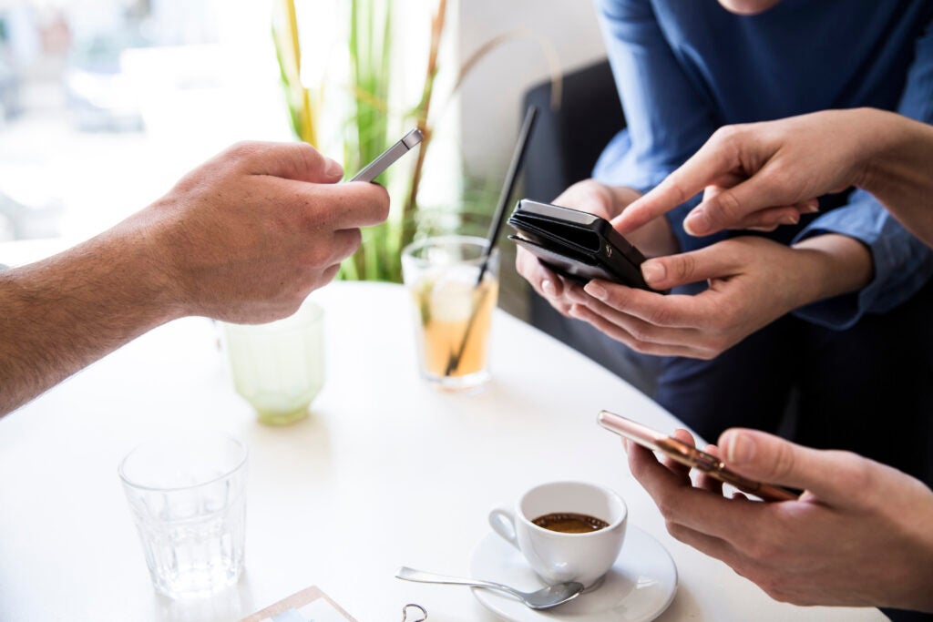 Three people at a table with phones on hand