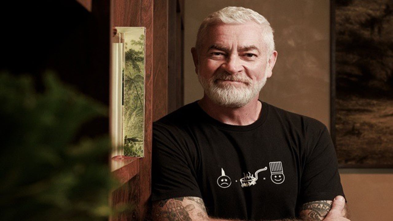 Man on a laptop with suitcases in a hotel room.