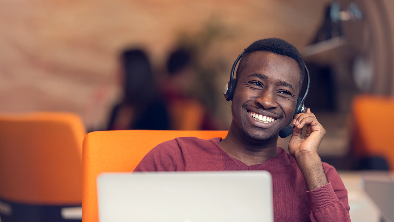 A man sitting at a desk with a laptop and a headset