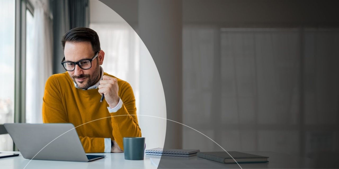 גבר אוחז בעט ומסתכל על מחשב נייד.