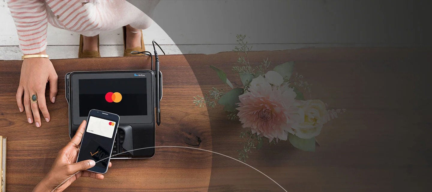 אדם מבצע רכישה עם הטלפון שלו במסוף תשלום של בית עסק.