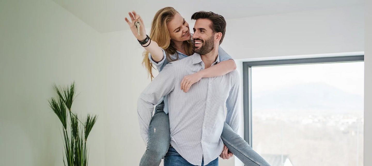 Man and a woman happily walking into their new home with keys after securing a mortgage
