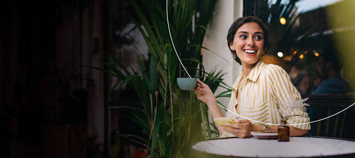 Žena sjedi i drži šoljicu u ruci.