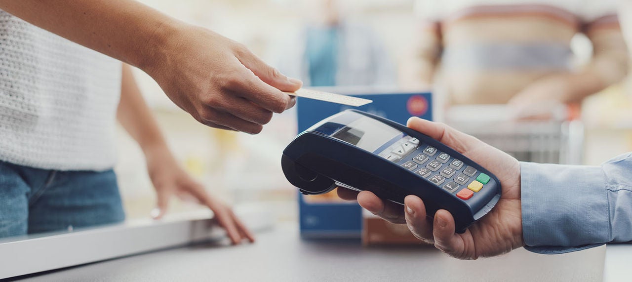 Customer in supermarket making a contactless credit card payment using a POS terminal
