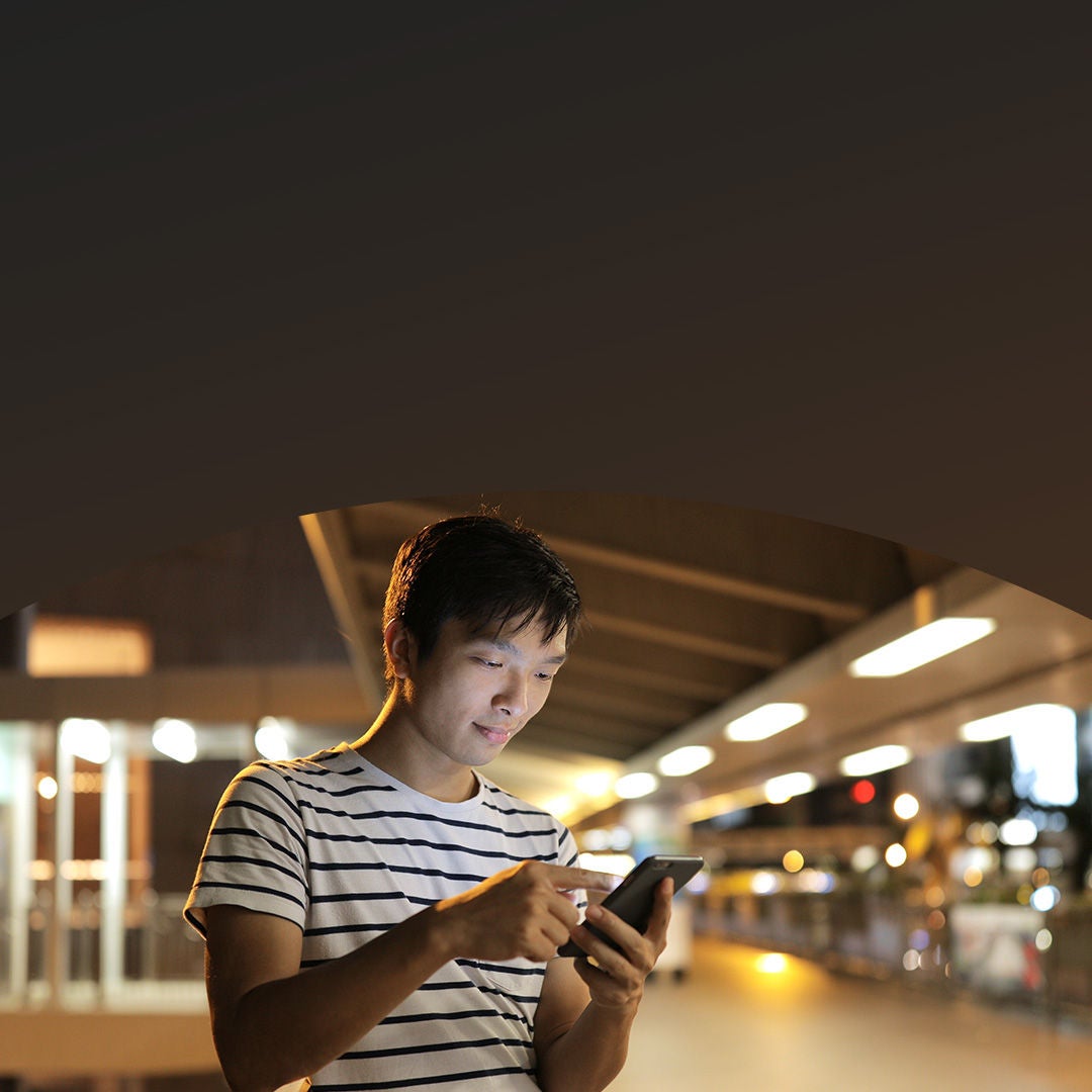 man using phone outdoors at night.