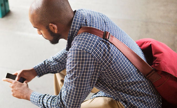 Man using his phone wearing a red bag