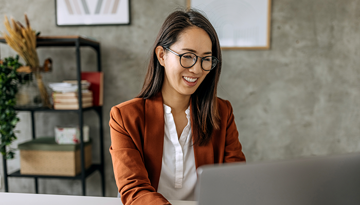 Woman happily doing work in the office on her laptop