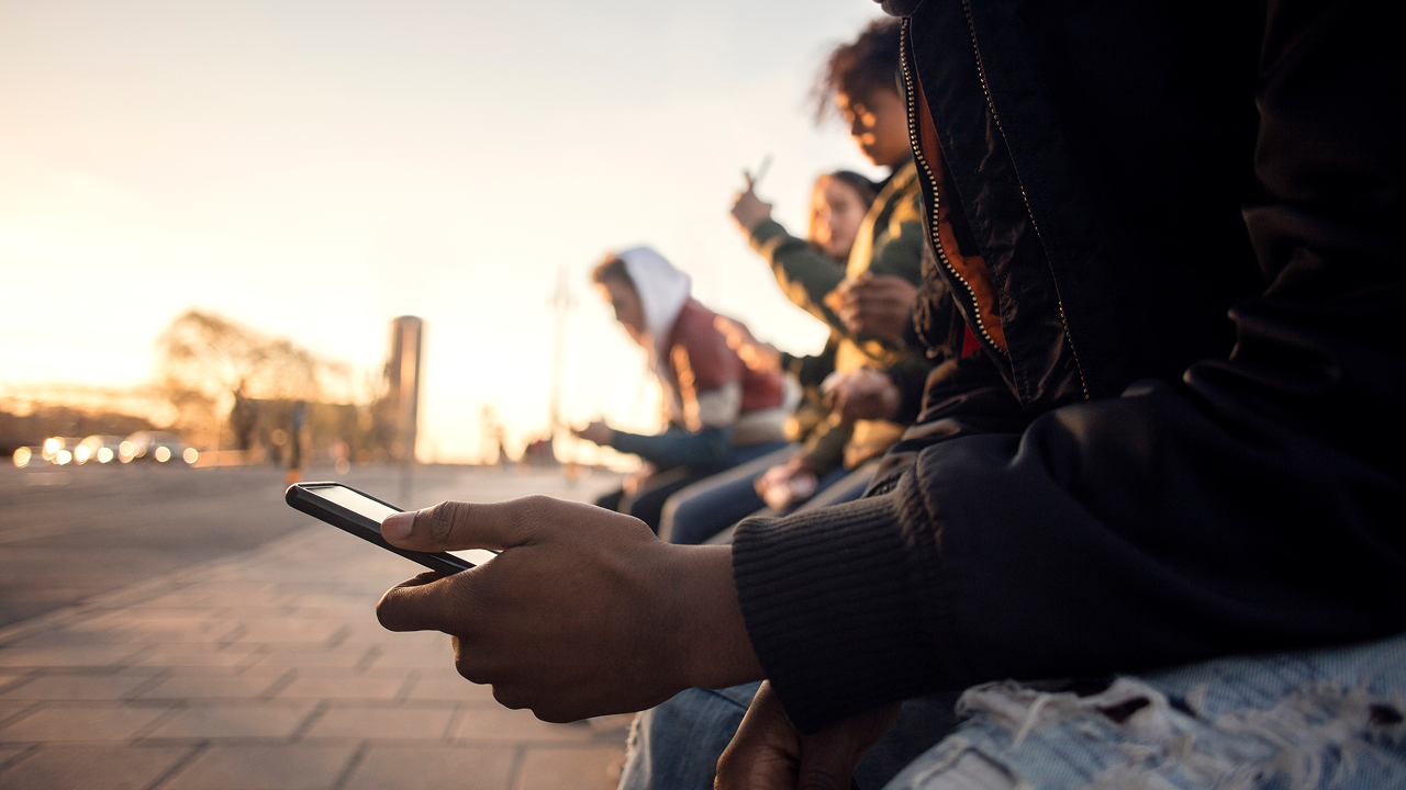 A young person sitting on a bench using a cell 